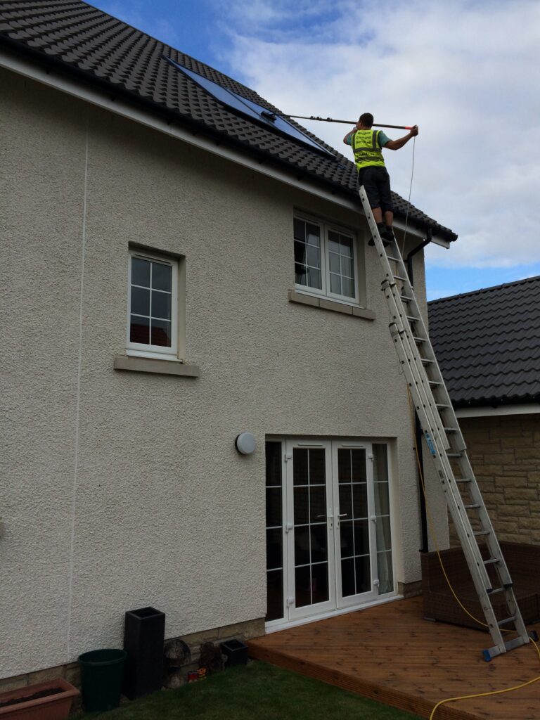 window cleaner up a ladder cleaning solar panels dangerously